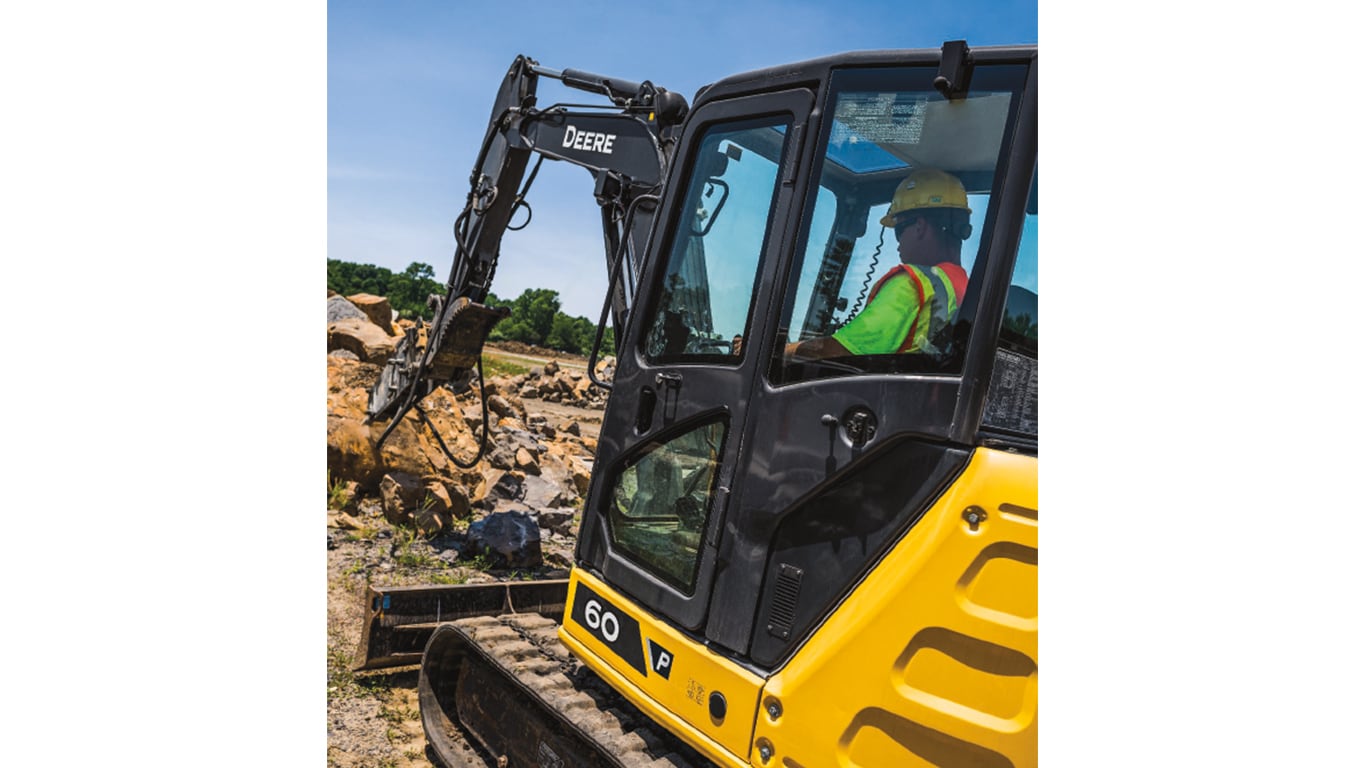 An operator using a 60P-Tier Excavator to scoop rocks at a worksite.