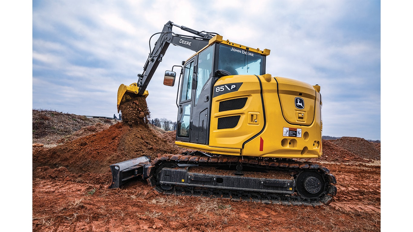 A side view of the 85P-Tier Excavator dumping dirt onto a pile at a worksite.