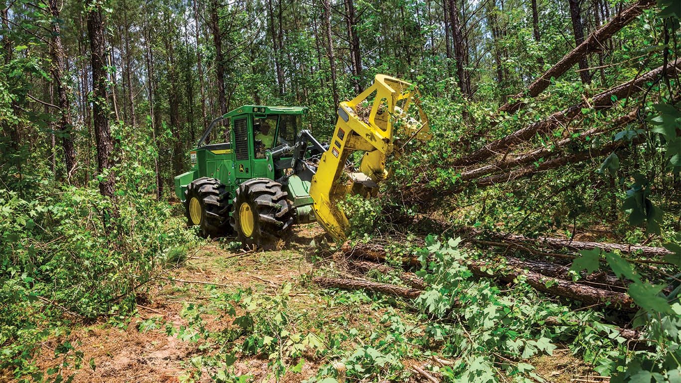 A John&amp;nbsp;Deere tracked felled buncher felling a tree in a forest.