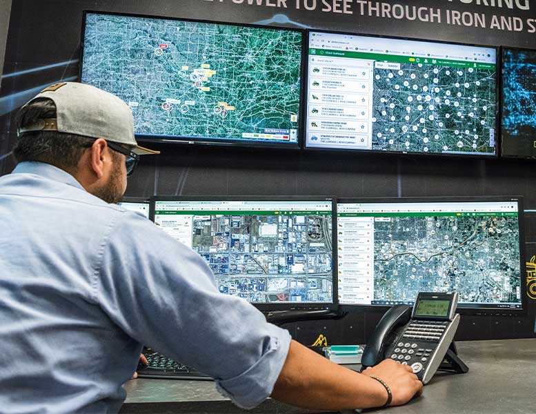 A person monitors screens with maps and machine data