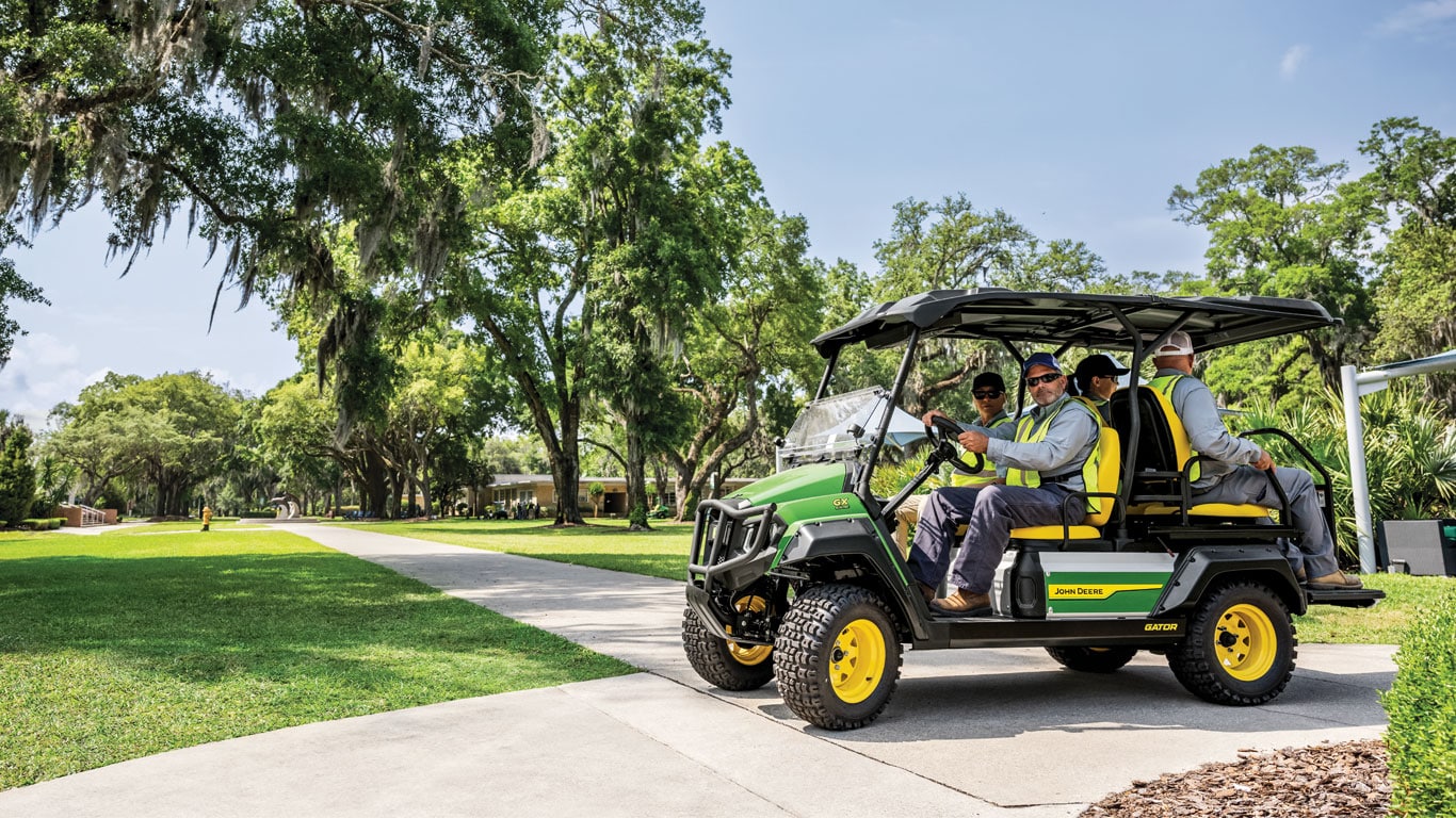 our professional landscaping contractors sit inside of the new John Deere GX electric Gator as one of the drives the vehicle in a public area