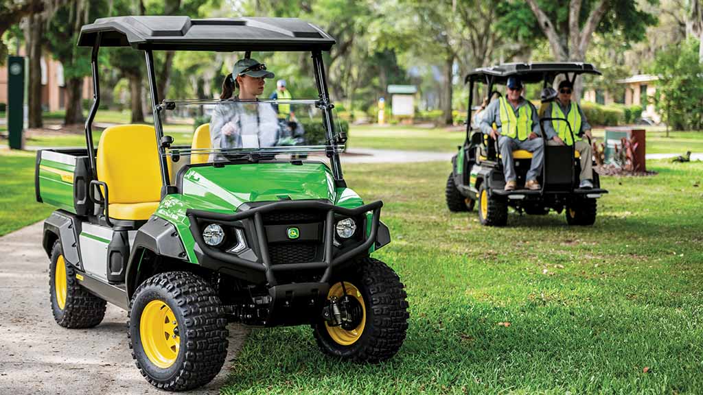 A green GX Gator with a single driver and GX Crew Gator with four passengers being driven around.