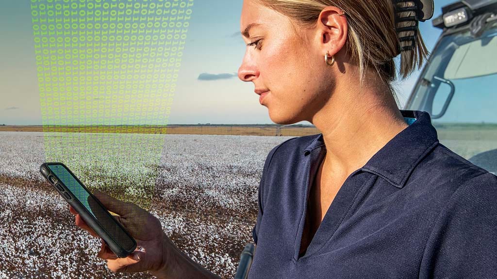 a close-up shot showing a female farmer in a cotton field, checking her John&nbsp;Deere Operations Center&trade; account on their mobile phone