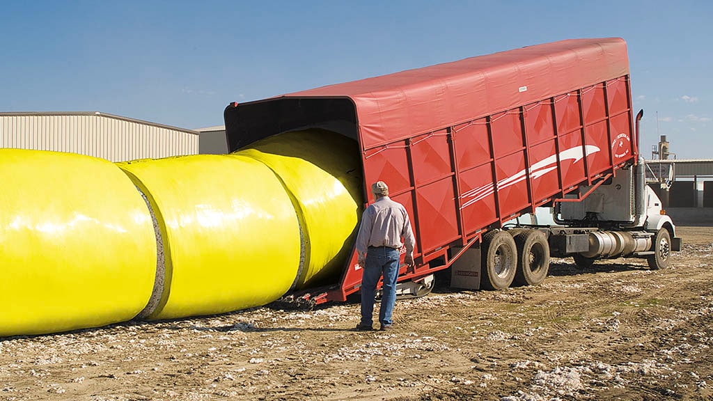 Large yellow tube connected to red covered flat bed truck