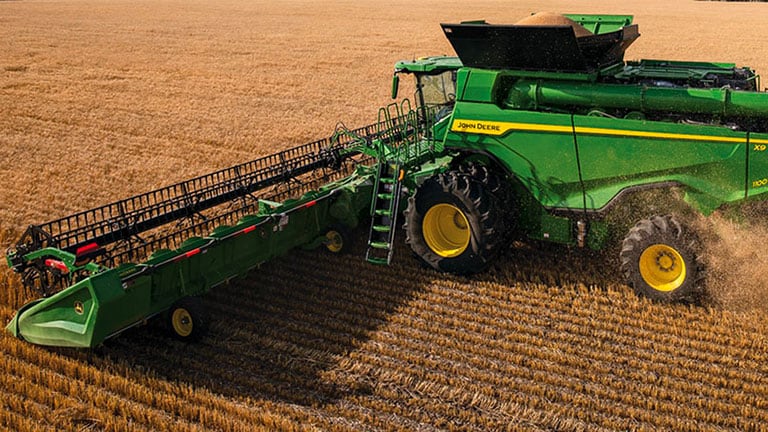 Photo of a John Deere X9 Combine harvesting wheat with a draper head