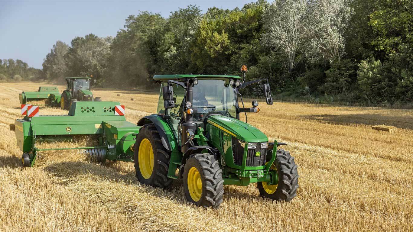 5 Series Tractor pulling an S200 small square baler in a field of hay.