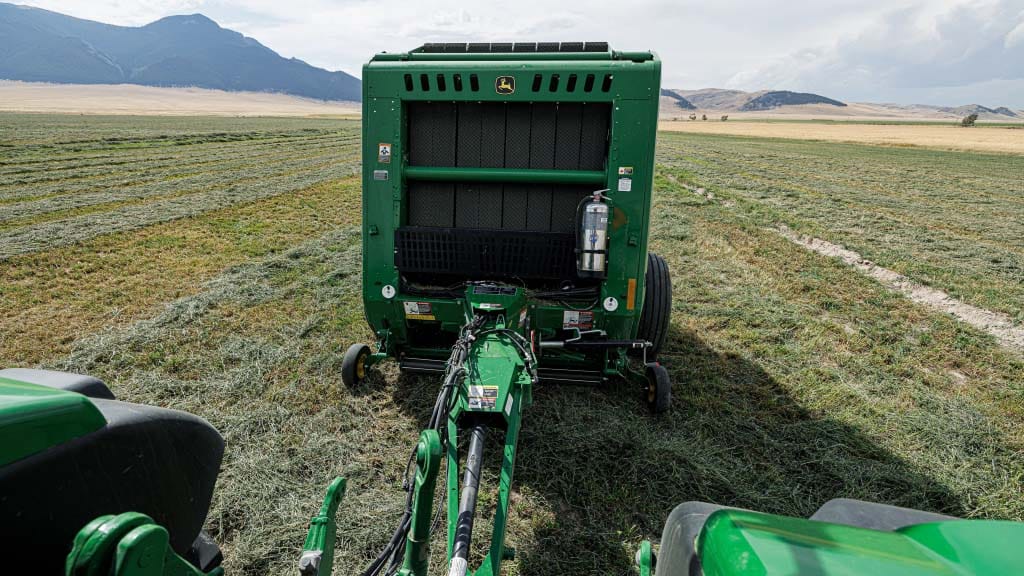 A tractor operating a 1 Series Round Baler with weave automation.