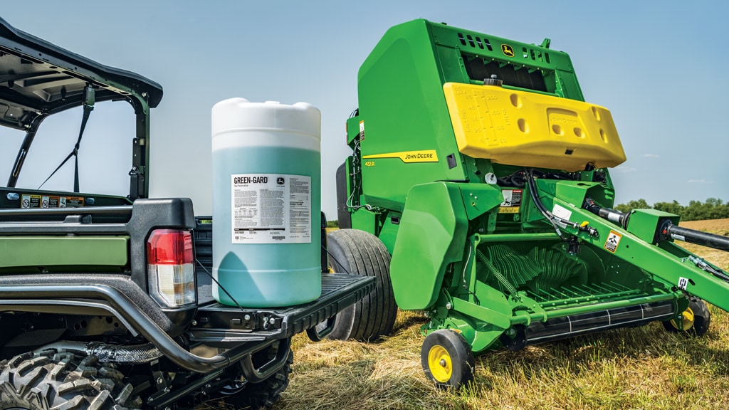 Image of Green-Gard Preservative tank in bed of Gator™ Utility Vehicle with Round Baler in the background