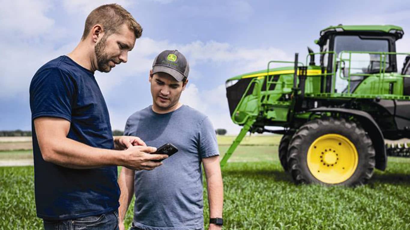 Two growers meeting in the field by the sprayer.