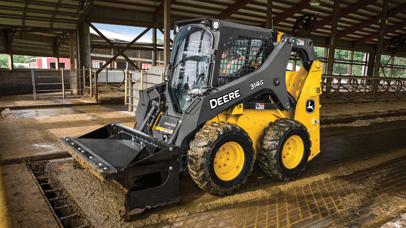 314G Skid Steer with material scraper working in a livestock confinement.