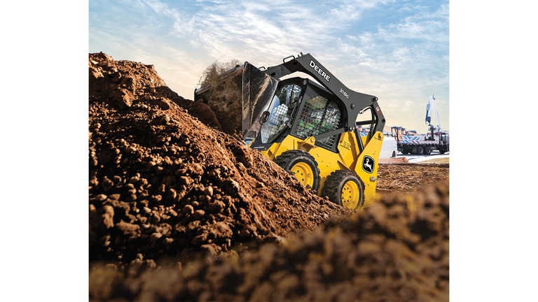 A 318G Skid Steer moves rock and dirt on unleveled terrain.