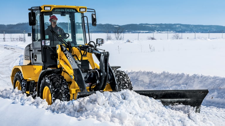 A 324K wheel loader with BL10B snow blade attachment plowing snow