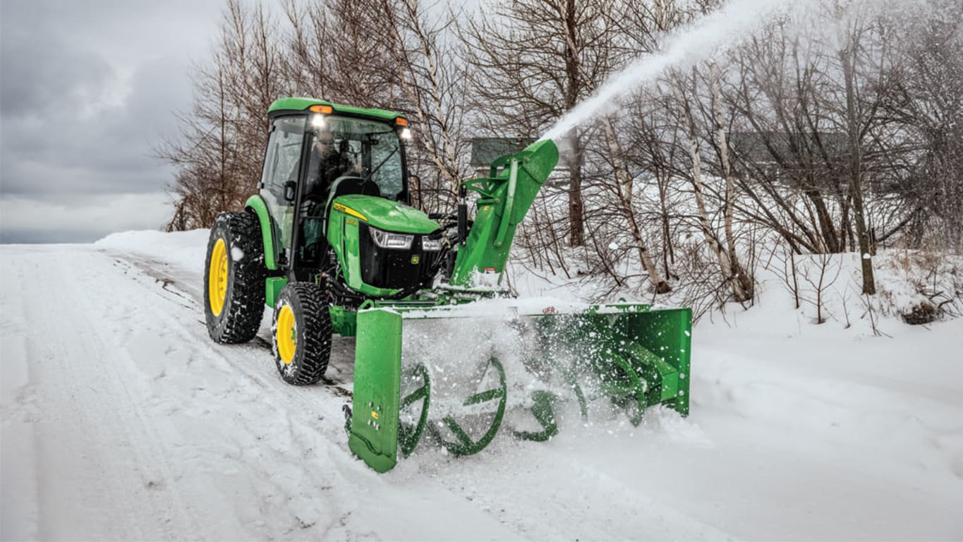Tractor plowing snow on a road using a Frontier SB1280F Front Mounted Snowblower with an 80-inch clearing capacity.