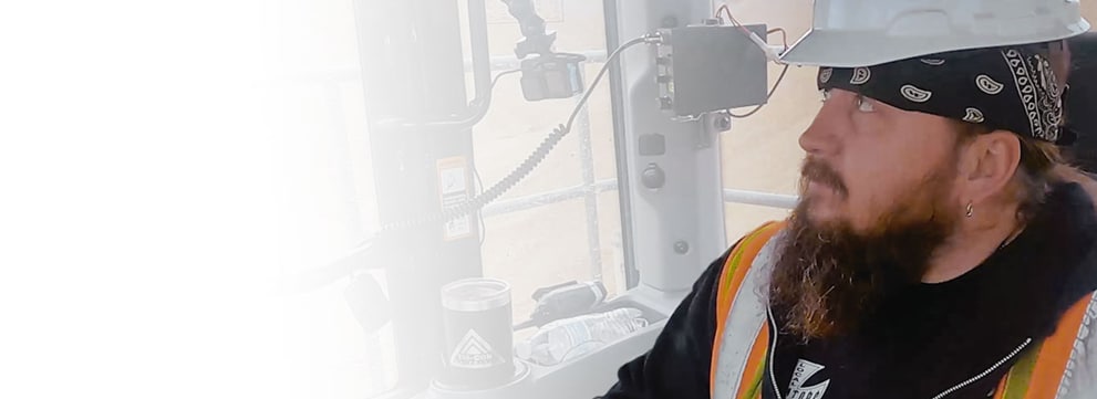 Bob Haun inside a cab operating equipment wearing a hard hat