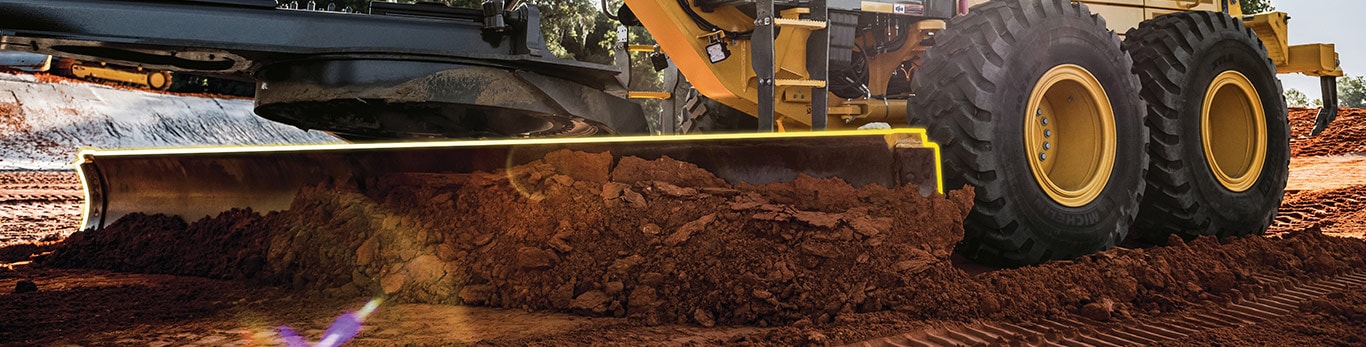 A John Deere motor grader pushes dirt, with its blade lighting up to indicate automation.