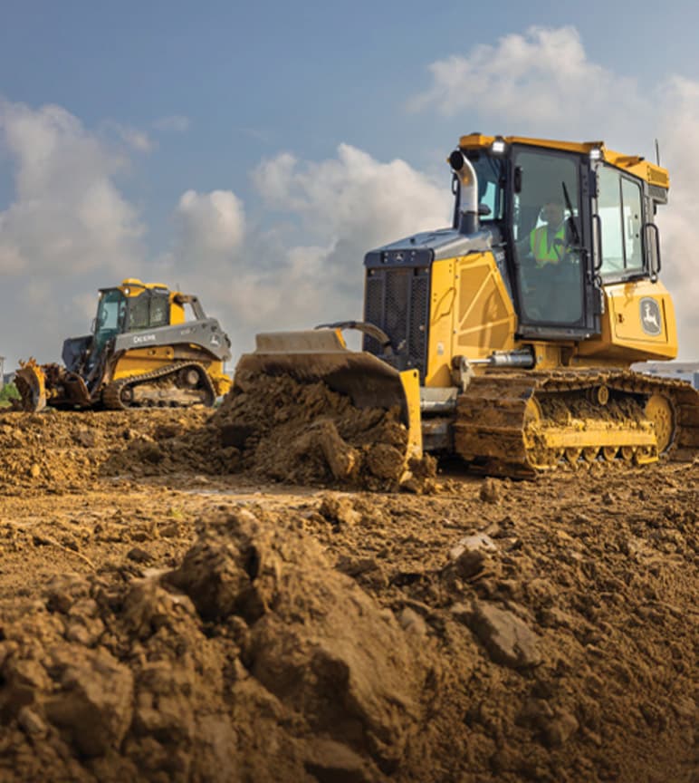 Two construction vehicles, a bulldozer and a skid steer loader, moving dirt on a construction site.