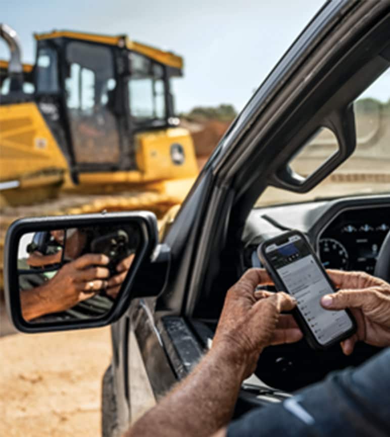 A construction worker in a truck interacting with a mobile phone on a jobsite