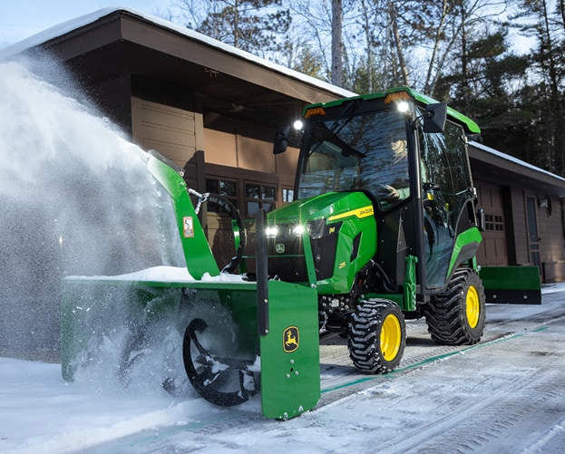 green and yellow tractor blowing snow