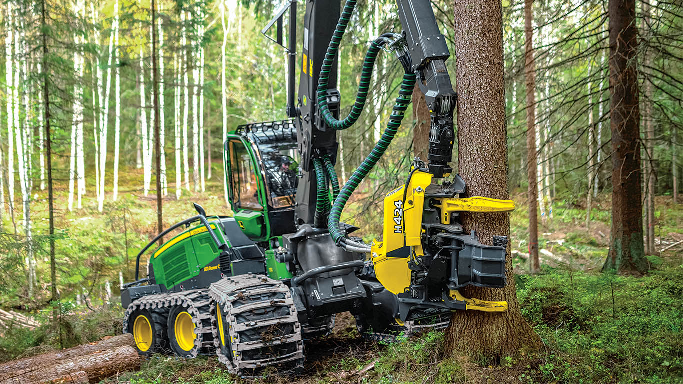 A John&nbsp;Deere wheeled harvester felling a tree in a snowy forest.