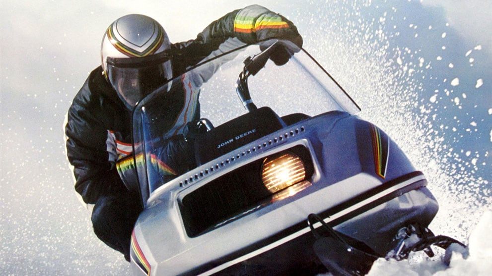 Man in full gear rides a snowmobile