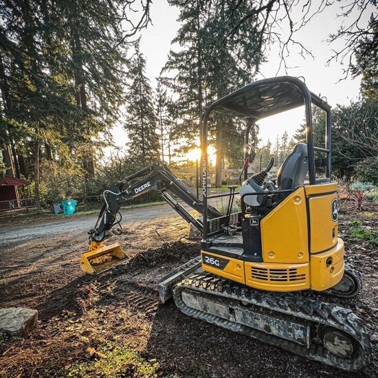 John Deere Compact Excavator digging in the setting sun.