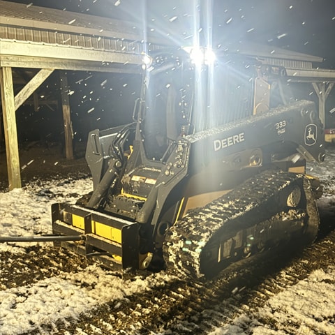 A 333 P-Tier with a bale spear, warming up as snow falls around it.