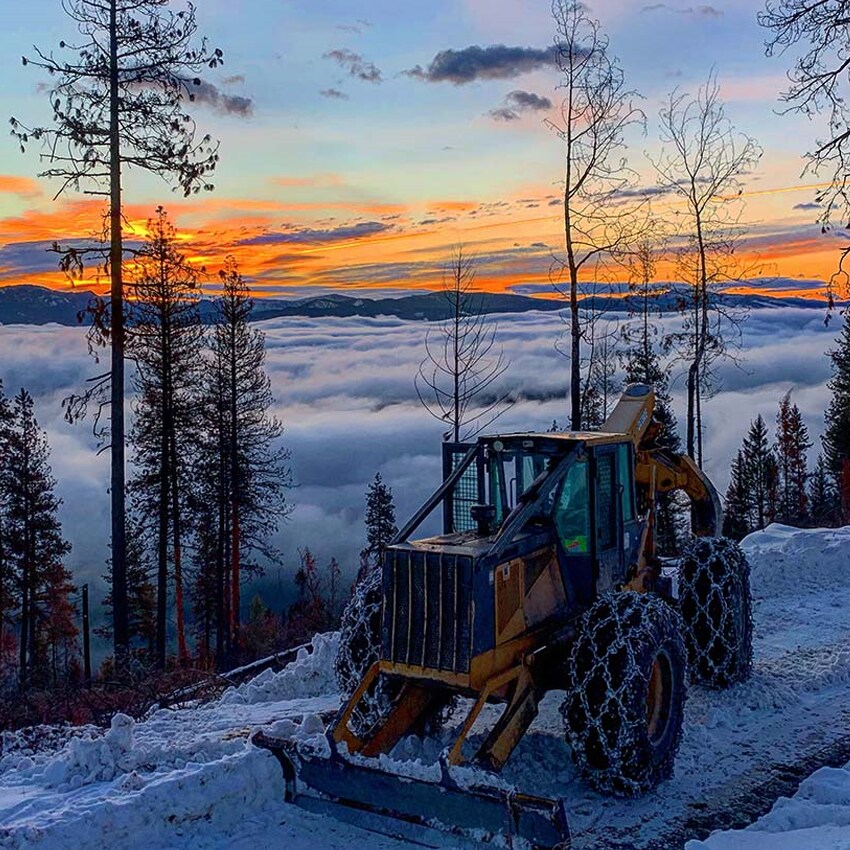 John Deere Tractor Loader pushing snow on winding dirt road.