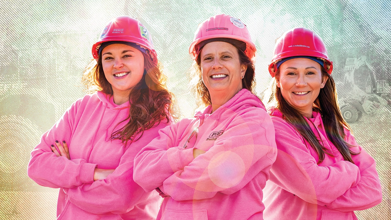 Missy Madden, Alescia Pierce, and Erin McFague standing together wearing pink sweatshirts and pink hard hats.