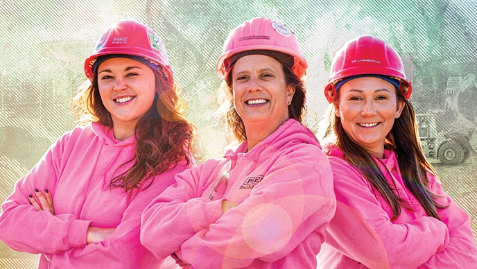 Missy Madden, Alescia Pierce, and Erin McFague standing together wearing pink sweatshirts and pink hard hats.