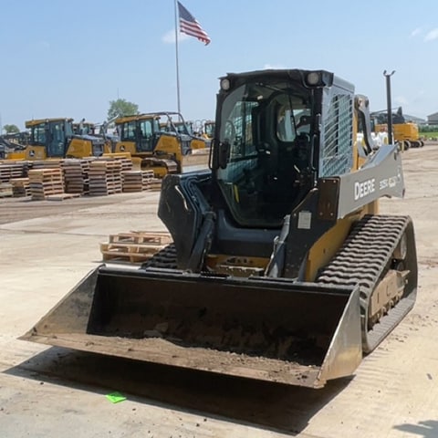 A 325 G-Tier Compact Track Loader sitting in a garage door way.
