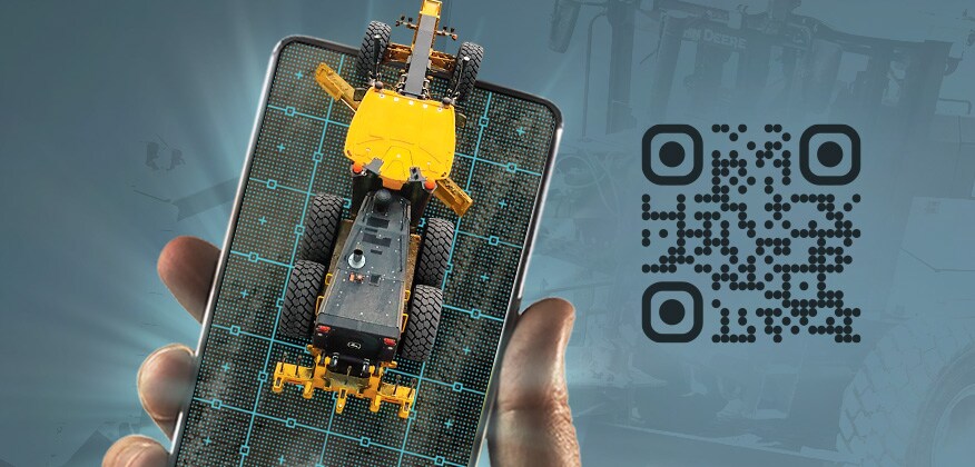 Hand holding a mobile device with a top view of a motor grader driving off its screen to represent augmented reality.