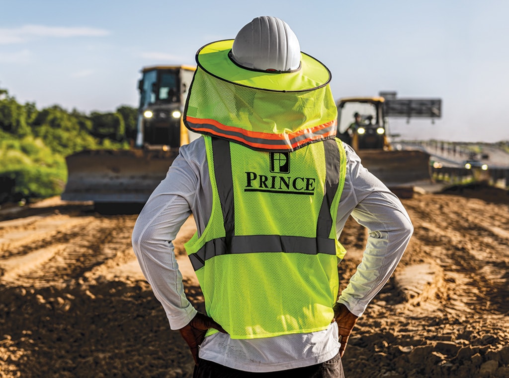 A Prince Contracting employee is facing toward the two dozers behind her as they grade the area where the road is being widened.