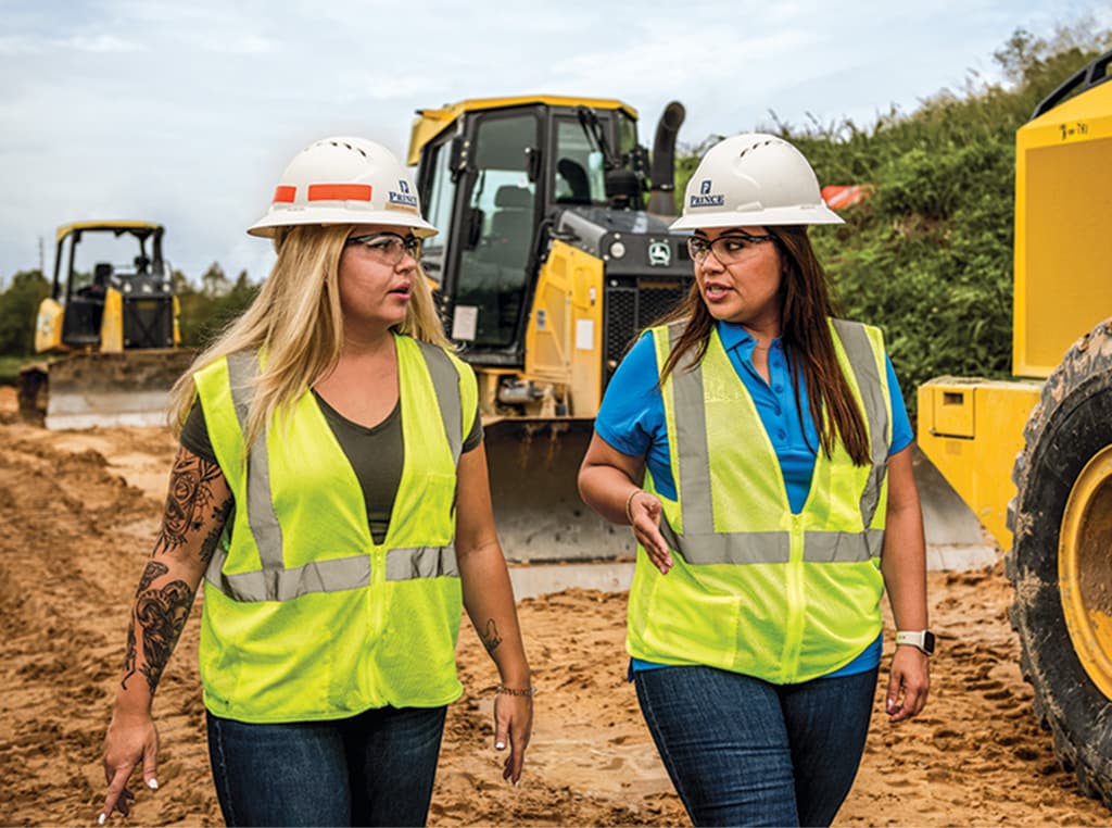 Leah and Andrea walk past a 450K LGP Dozer, a 650K LGP Dozer, and a 524 P-Tier Wheel at the end of their shift. 