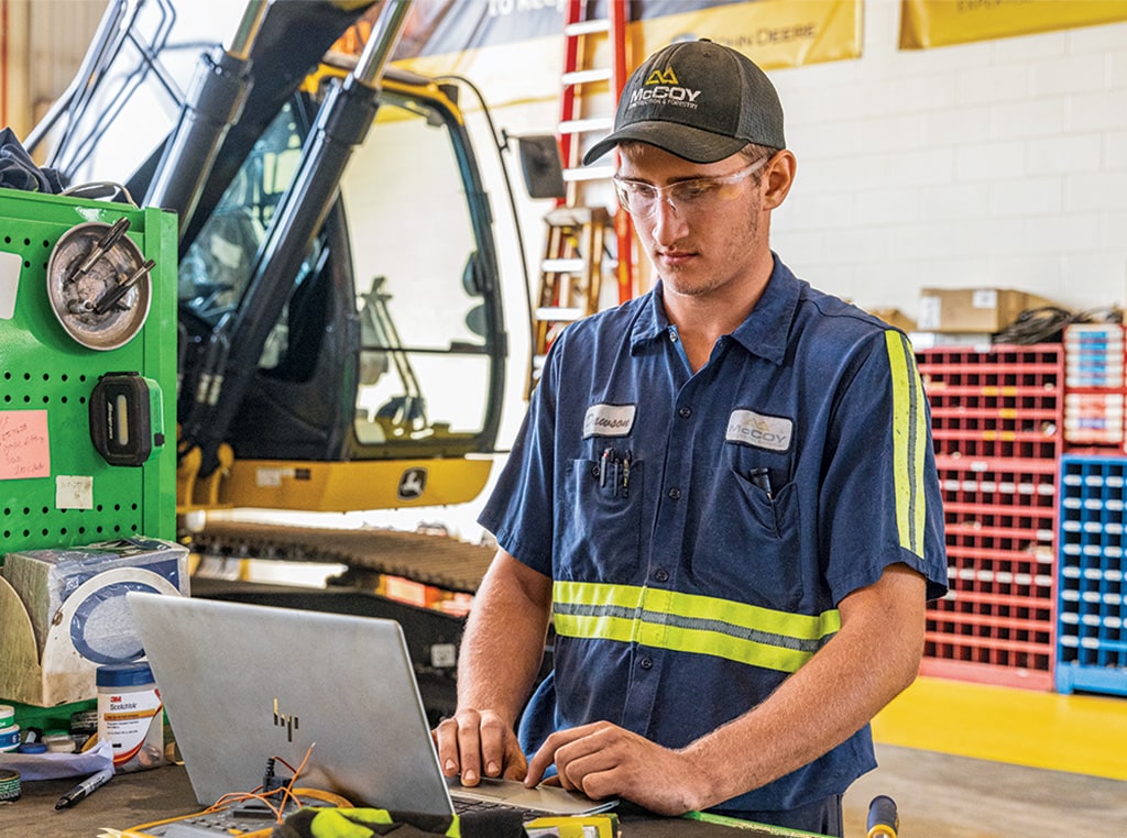 Dawson uses his laptop computer in the service bay and reviews the machine’s data to determine its maintenance needs as part of the John Deere Protect program.
