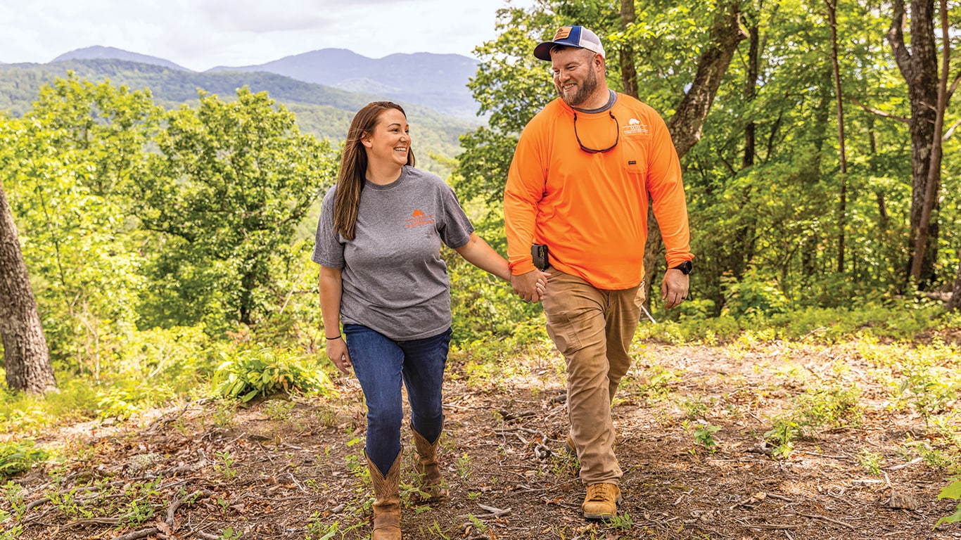 Ashley and Miles Holden hold hands as they take a walk in a forest of the Blue Ridge Mountains.