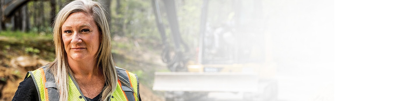 Jennifer Morris stands in front of a John Deere 50G Compact Excavator.