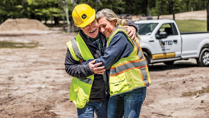 Jennifer Morris of GFM Enterprises and Joe Huber of United Construction & Forestry share a laugh and a hug on a jobsite in Cape Cod.