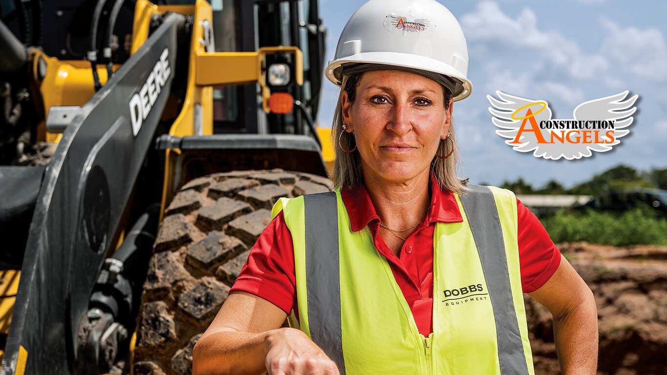 Kristi rests her arm on the bucket of a 524 P-Tier Wheel Loader on a roadbuilding jobsite in Florida.
