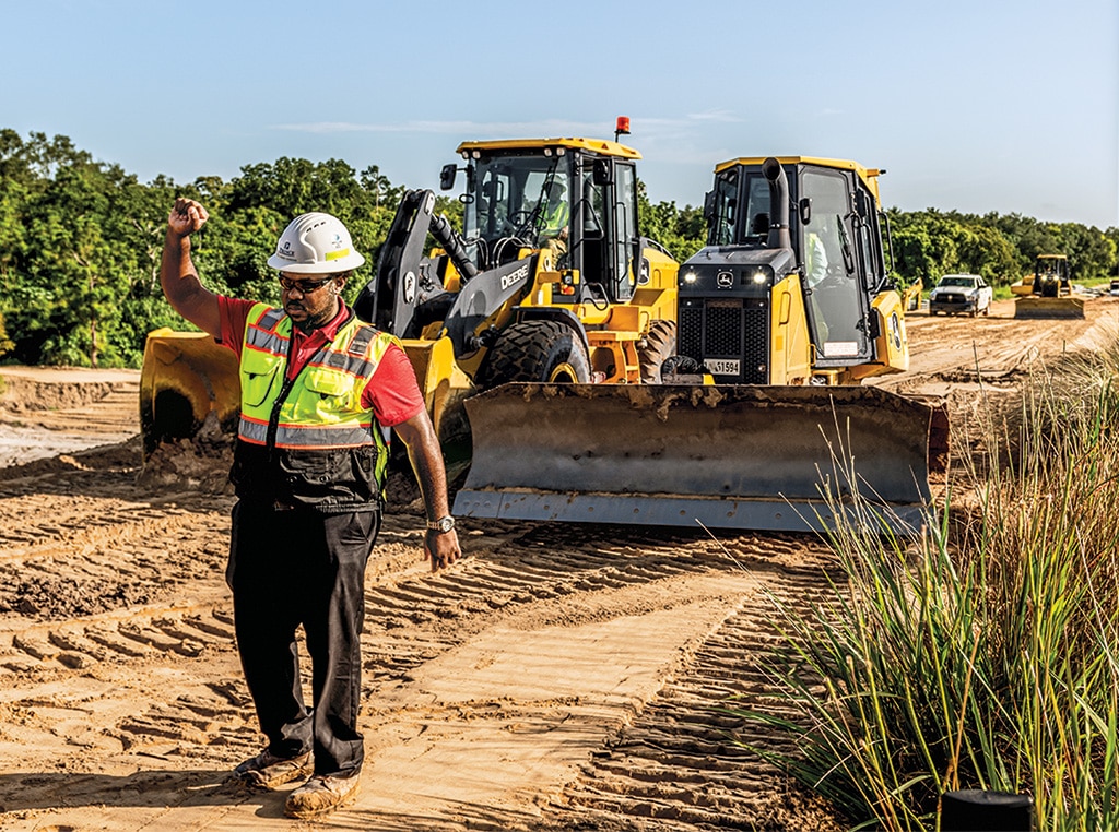 Robinson raises his right hand to communicate with his crew and keep workers safe as a 650K LGP Crawler Dozer and 524 P-Tier Wheel Loader shape a stretch of land in Florida.