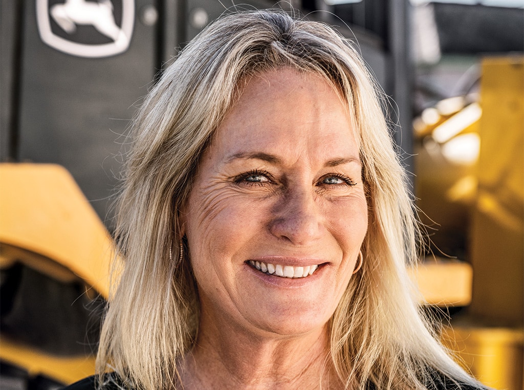 Julie poses for the camera in front of a John Deere wheel loader. 