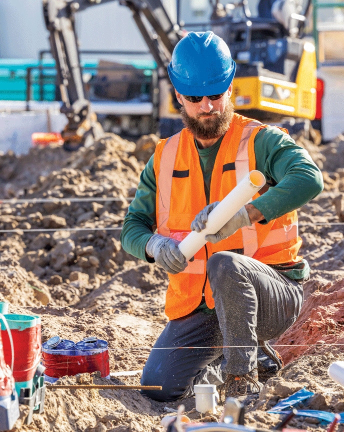 A worker adjusts underground tubing on a jobsite