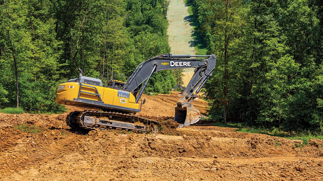A John Deere 350 G-Tier Excavator digging dirt on a hill side.