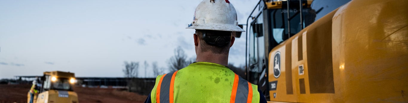 operator walks towards an excavator on a jobsite