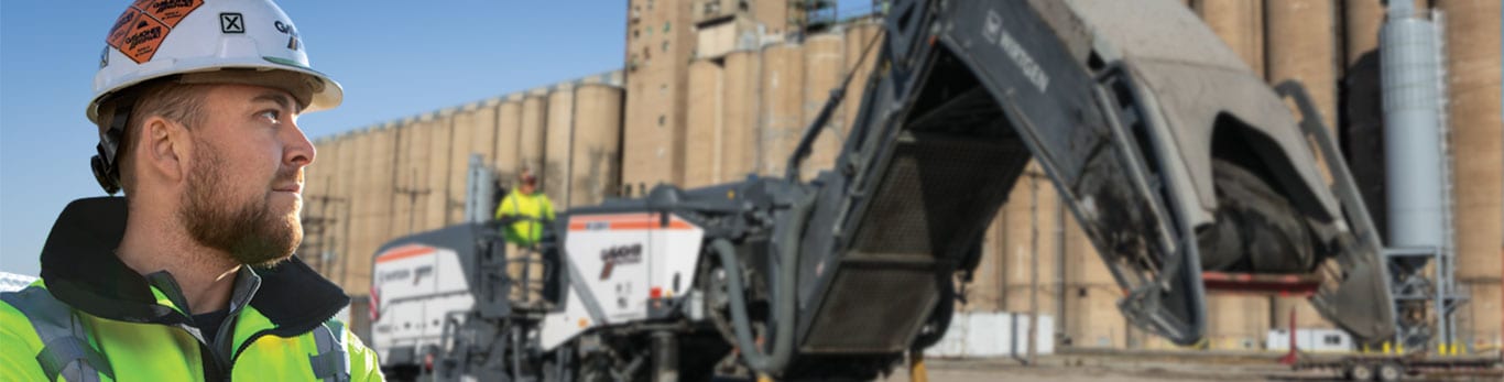 Chris looks over his shoulder at a large piece of machinery in the background