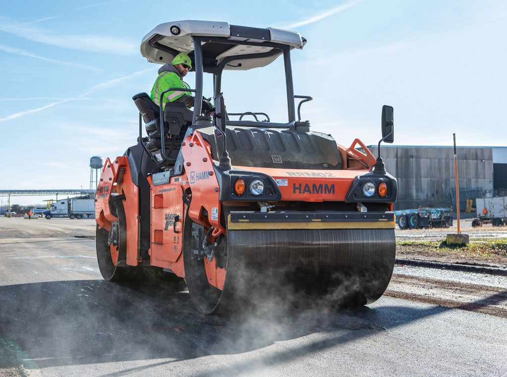 A drum roller compacts fresh asphalt on a new road