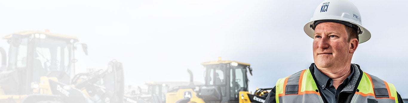 Aaron Kaden stands in front of John Deere 644 X-Tier Wheel Loaders at Kansas City International Airport.