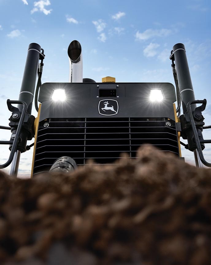 A close-up shot of a John Deere 850 X-Tier Dozer’s front blade as it pushes a large amount of dirt.