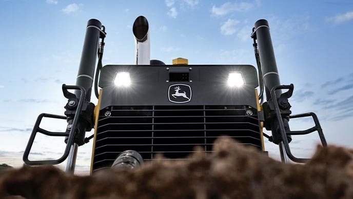 A close-up shot of a John Deere 850 X-Tier Dozer’s front blade as it pushes a large amount of dirt.