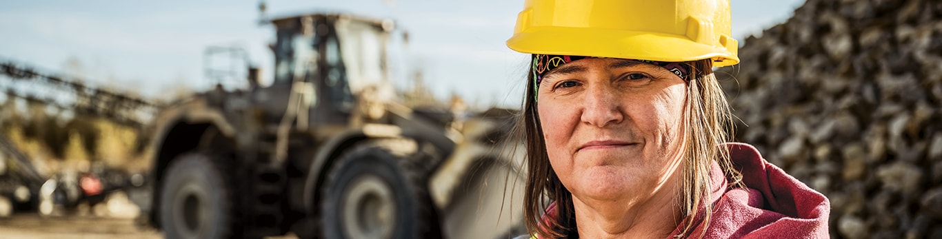 Head shot of Lisa Nanninga in front of a John Deere Wheel Loader and pile of rock