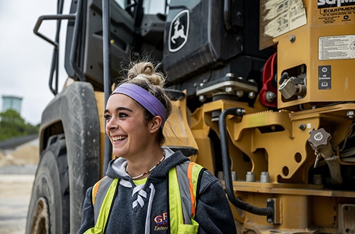 Brooke Wrightington, an operator for GFM Enterprises, stands besides a 260E Articulated Dump Truck. 